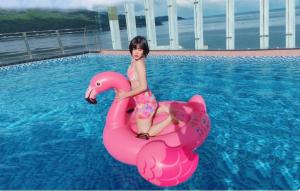 a young girl riding a pink swan in a pool at DAO NGOC BEACH HOTEL Da Nang in Danang
