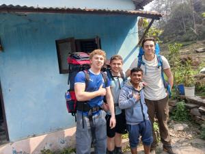 a group of people standing in front of a blue house at Hotel Hilton Annapurna Garden in Ghanpokhara