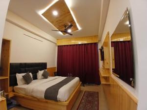 ein Schlafzimmer mit Bett und Deckenventilator in der Unterkunft Hotel Cloud Hills in Dharamsala