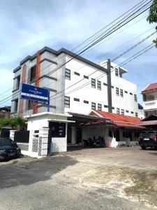 a white building with a blue sign in front of it at Hotel Bhakti Syariah in Padang