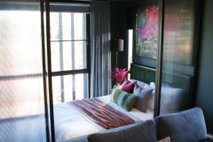 a bedroom with a bed and a large window at Green Rooms Braddon - Designer Micro Apartments in Braddon