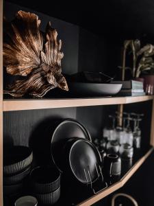 a shelf with plates and bowls and dishes on it at Green Rooms Braddon - Designer Micro Apartments in Braddon