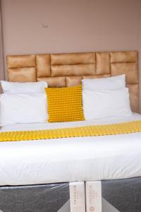 a bed with a yellow pillow and pillows on it at Pamusha Motel in Ngesi +4 photos