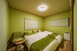 a bedroom with a large bed with green walls at 夢思苑 別府 in Beppu