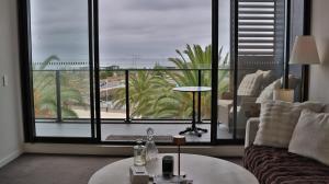 a living room with a couch and a large window at Beach paradise in Werribee South