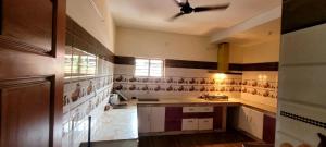 a large kitchen with white counters and a ceiling fan at K Apartment in Varkala