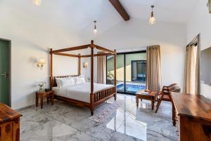 a bedroom with a canopy bed and a desk at Merriment Luxury Resort & Private Pool Villa Near Mount Abu, Abu Road in Bhīmānia