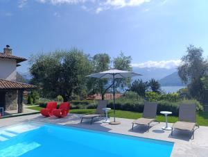 a swimming pool with chairs and an umbrella at Design Villa in Tremezzina Villarnona Lake Como in Mezzegra