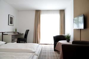 Cette chambre comprend deux lits, un bureau et une fenêtre. dans l'établissement Arnimsruh Hotel garni, à Lübeck