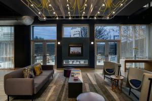 a living room with a couch and chairs and windows at Aloft by Marriott Houston by the Galleria in Houston