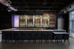 a bar with stools in a room with alcohol bottles at Aloft by Marriott Houston by the Galleria in Houston