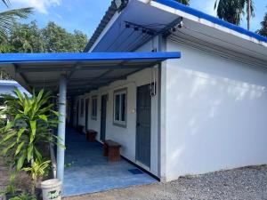 a white building with a blue roof and a porch at Double P in Ban Phlong Sawai