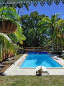 a swimming pool in a yard with palm trees at La Palmeraie Créole in Sainte-Marie