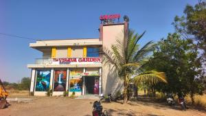 a building with a palm tree in front of it at Hotel Visava Restaurant & Lodging in Vaghunde Budrukh