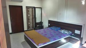 a bedroom with a bed with a purple bedspread at Hotel Visava Restaurant & Lodging in Vaghunde Budrukh