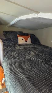 a bed with a comforter with a cow pillow on it at Tinyhouse op de Veluwe, het buitenleven in Oene