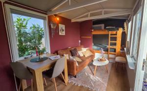 a living room with a couch and a table and a bed at Tinyhouse op de Veluwe, het buitenleven in Oene