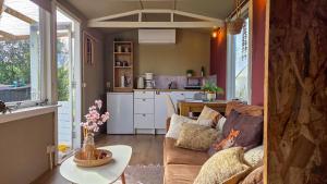 a living room with a couch and a table at Tinyhouse op de Veluwe, het buitenleven in Oene +37 photos