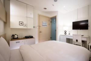 a white room with a bed and a kitchen at Wemeet Hotel Taipei in Taipei