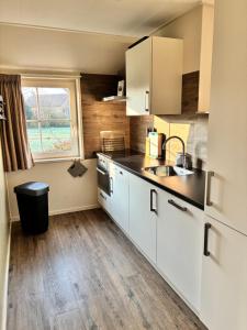 a kitchen with white cabinets and a sink and a window at Vakantiewoning Meeuw in Hollum