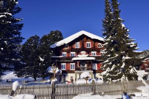 a house covered in snow with a fence and a tree at Ferienhaus Chalet Riedji in Furna