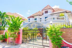 ein großes weißes Haus mit einem schwarzen Tor in der Unterkunft RATANA VILLA - PATTAYA HOLIDAY HOUSE WALKING STREET 7 bedrooms in Pattaya South