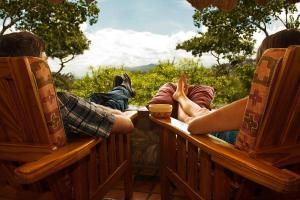 a group of people sitting on benches looking out at the mountains at Musangano Lodge in Odzi