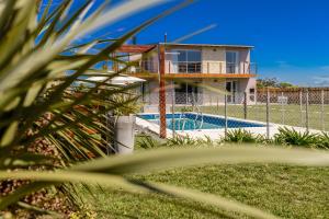 a house behind a fence with a swimming pool at Radazul Apart de Mar & Campo in Chapadmalal