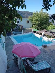a pink umbrella and chairs next to a swimming pool at "Casa ibero" Bubion in Bubión