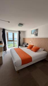 a bedroom with a large bed with orange pillows at Logis Hôtel Le Rochelois in La Rochelle
