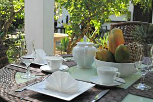 a table with plates and cups and a bowl of fruit at Wasantha Garden Hotel Restaurant & Ayurvedic Treatment in Weligama