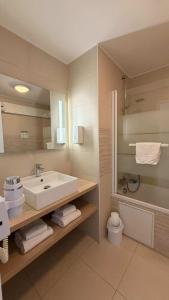a bathroom with a sink and a toilet and a mirror at Logis Hôtel Le Rochelois in La Rochelle