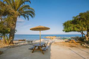 a picnic table and an umbrella on the beach at Elya Beach Luxury Suites in Ayios Theodhoros