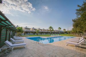a swimming pool with lounge chairs in a resort at Elya Beach Luxury Suites in Ayios Theodhoros