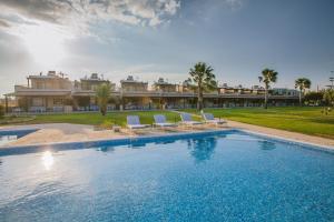 a pool with chairs and a house in the background at Elya Beach Luxury Suites in Ayios Theodhoros