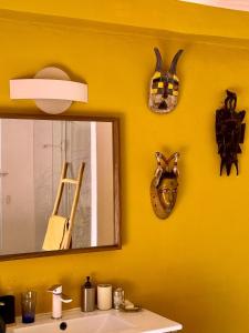 a bathroom with a yellow wall with a mirror and a sink at Chambre 2 personnes Maison Saint Jean in Château-Chalon +25 photos