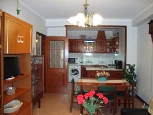 une cuisine et une salle à manger avec une table et des fleurs rouges dans l'établissement Apartamento Artur, à Lousã