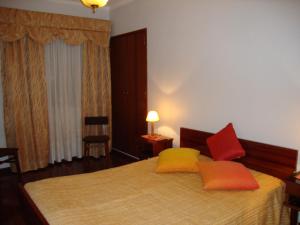 a bedroom with a bed with two orange and yellow pillows at Apartamento Artur in Lousã
