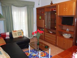 ein Wohnzimmer mit einem Sofa und einem Tisch mit Blumen darauf in der Unterkunft Apartamento Artur in Lousã