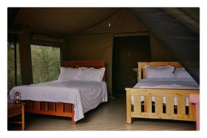 two beds in a room with a tent at NATURE LOVERS ADVENTUREs in Maasai Mara National Reserve