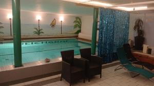 a swimming pool in a room with chairs and a table at Pension Deichgraf Middelhagen in Middelhagen
