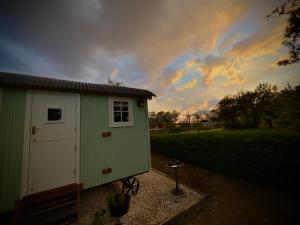 a green and white shed with a sky in the background at Luxury Shepherds hut with wood fired hot tub on Lincolnshire Coast in Mablethorpe