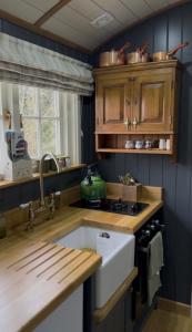 a kitchen with a sink and a stove top oven at Luxury Shepherds hut with wood fired hot tub on Lincolnshire Coast in Mablethorpe