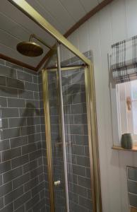a shower with a glass door in a bathroom at Luxury Shepherds hut with wood fired hot tub on Lincolnshire Coast in Mablethorpe