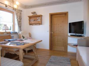 a living room with a wooden table and a television at Fewo Bergruah in Bad Bayersoien