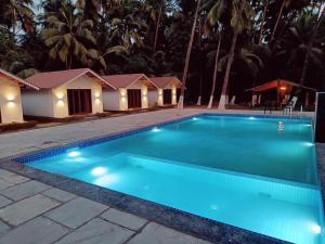a swimming pool in a resort at night at Palm Paradise Resort in Revadanda