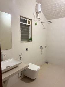 a bathroom with a sink and a toilet and a mirror at Palm Paradise Resort in Revadanda