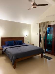 a bedroom with a bed with blue pillows and a ceiling fan at Palm Paradise Resort in Revadanda