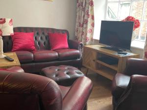 a living room with two leather couches and a television at The Bittern in Holt