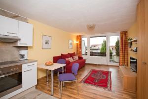 ein Wohnzimmer mit einem roten Sofa und einem Tisch in der Unterkunft Rosenalm Appartment 208 in Scheidegg